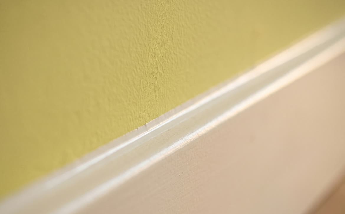 Strak afgewerkte kitnaad in de hoek tussen plint en wand